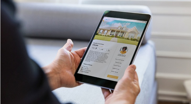 A homebuyer looks at an online listing for a property that's owned by a real estate investment trust.