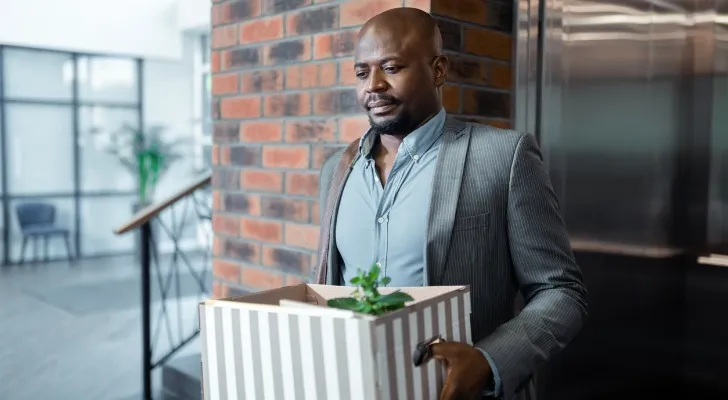 A man carries a box of his personal belongings on his final day of work at his company.