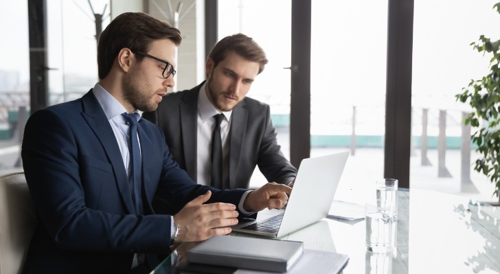 Two financial advisors reviewing candidate applications for an internship.