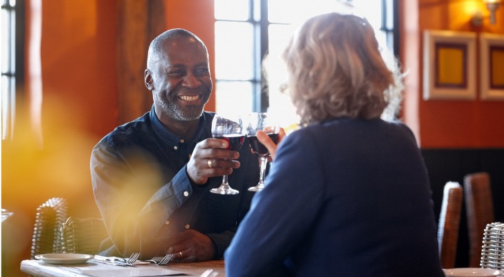 A married couple enjoys a glass of wine while out dinner.