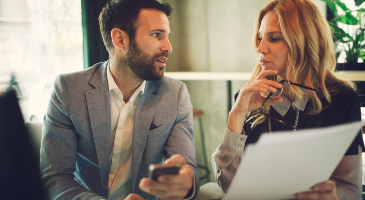 Two financial advisors reviewing a list with target clients.