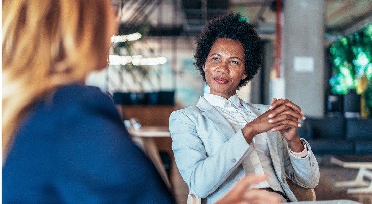 A financial advisor listens to a client during a meeting in her firm's offices.