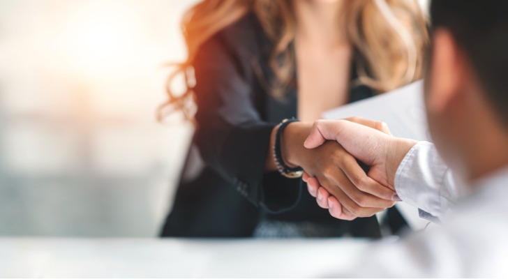 The owner of an RIA shakes hands with a compliance consultant after hiring her firm to provide compliance services.
