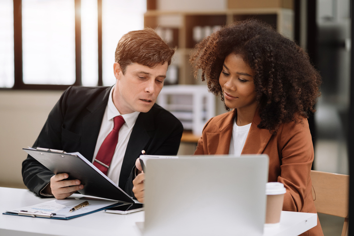 Two financial advisors reviewing their direct mail marketing strategy.