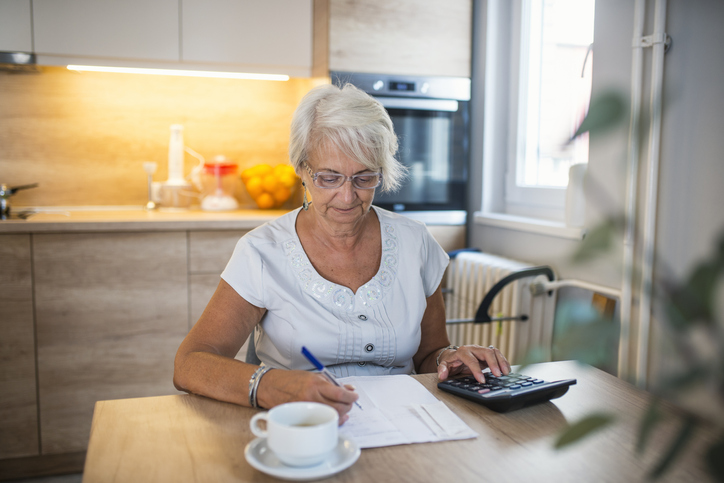 A senior woman calculating how much she has saved for retirement.