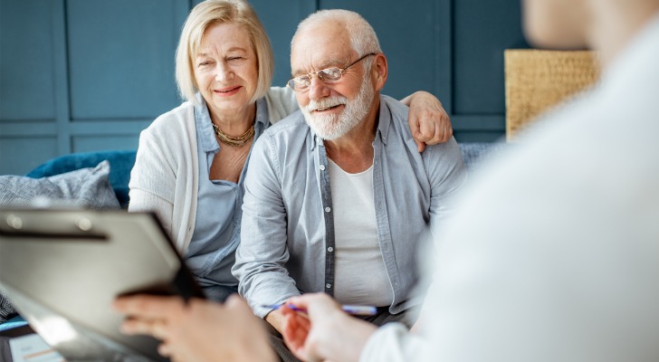 A senior couple signing a financial power of attorney after reviewing it.