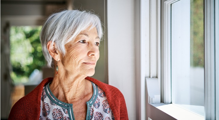 A recent widow gazes out the window while pondering her Social Security survivor benefits.