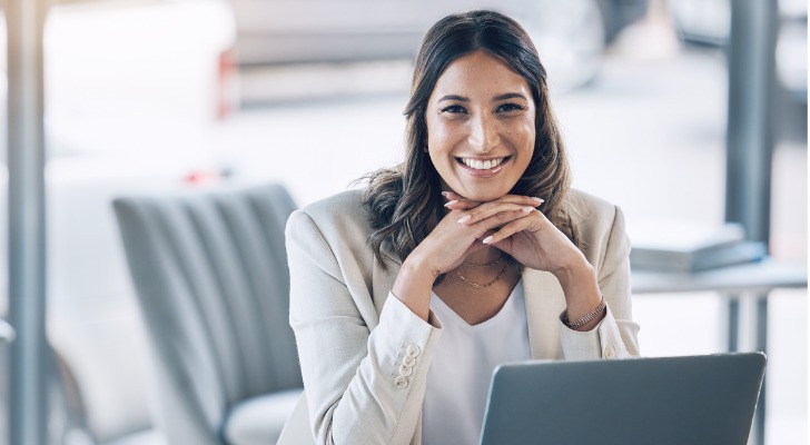 A financial advisor smiles as she drafts a prospecting email to a potential client.