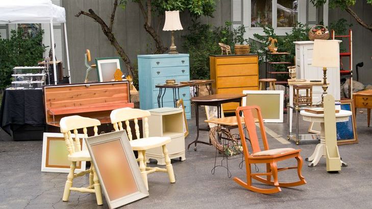 Furniture items are lined up outside a home during an estate sale.