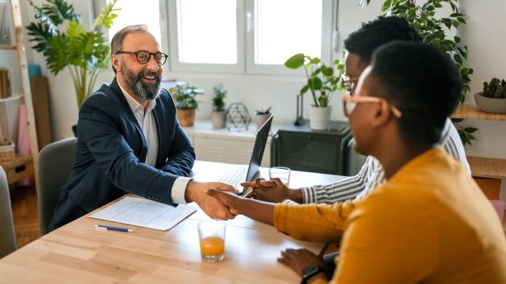 A financial advisor shakes hands with two clients after discussing their risk tolerance.