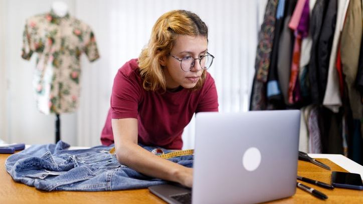 An employee of an estate sale company goes through various articles of clothing and logs their prices into a computer.