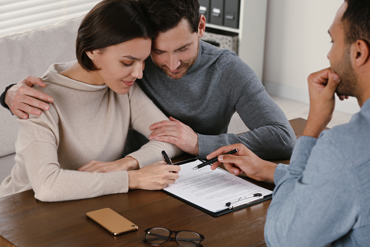 A couple signing documents for a mortgage application, which includes a gift letter.