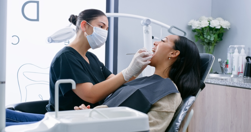 A dentist with a patient. The median dentist salary is $166,000 per year.