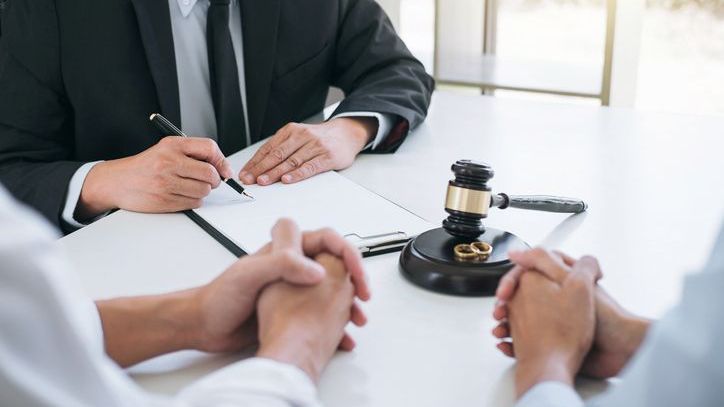 An attorney signs papers in front of two divorcing spouses.