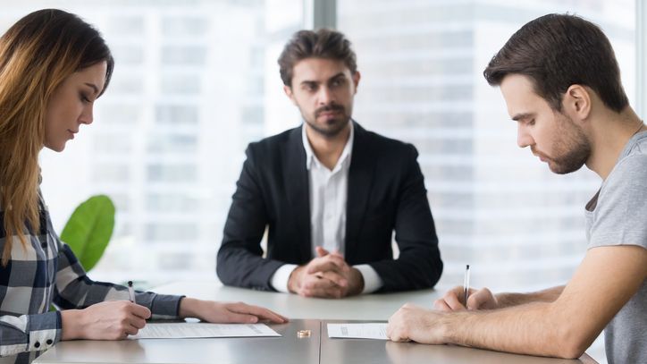 A divorcing couple signs a house buyout agreement in front of one of their divorce attorneys.