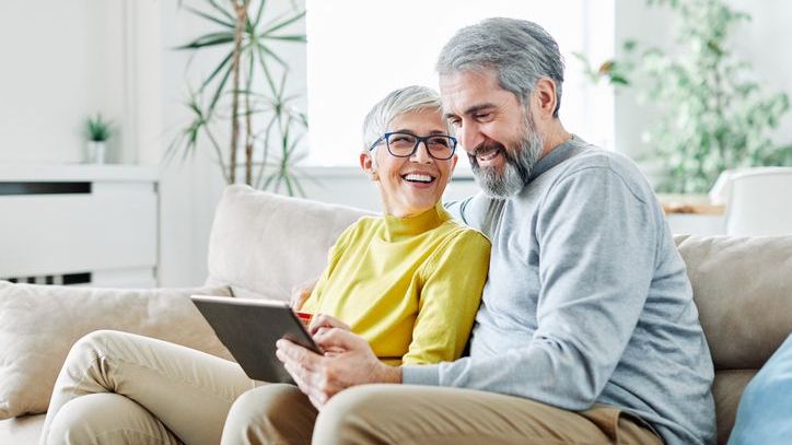 A couple looks at home listings on a tablet to determine if downsizing makes financial sense.