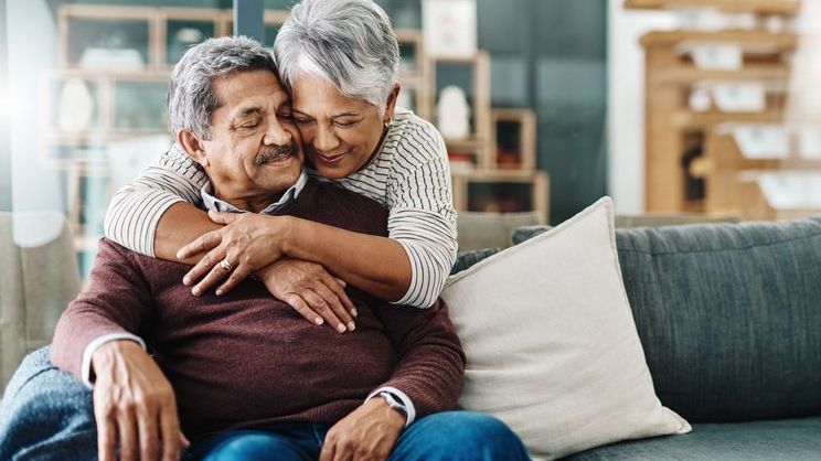 A woman hugs her husband after having a conversation about ways they can plan to protect their retirement income.