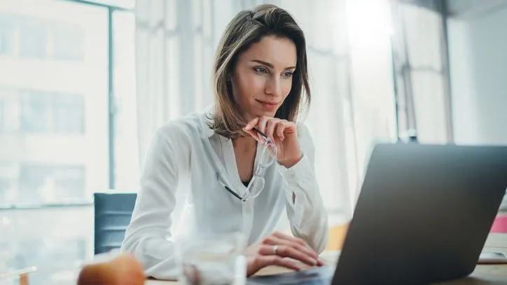 A woman reviews her finances on her laptop.