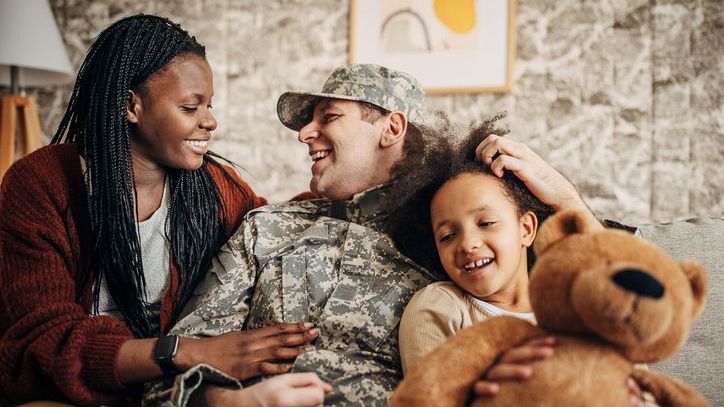 A soldier who's returning home from active duty is embraced by his wife and child.