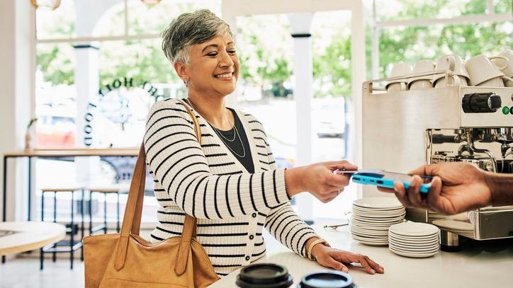 A woman pays for a coffee at a café with a prepaid card.
