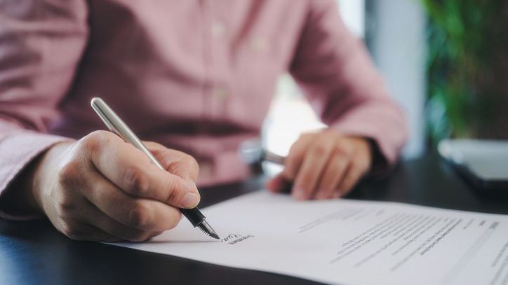 A person signs a trust document.