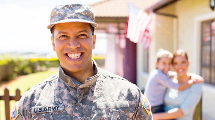 A member of the U.S. Army smiles in front of the home that he and his wife purchased with a VA loan.