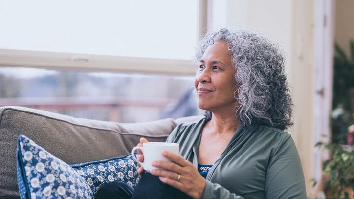A retiree enjoys a cup of coffee after doing some work on her finances.