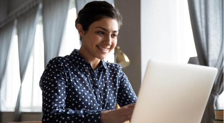 A woman smiles after passing the online exam for the certified personal finance counselor (CPFC) credential.