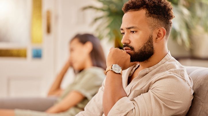 A divorcing couple sits at opposite ends of sofa after having an argument.