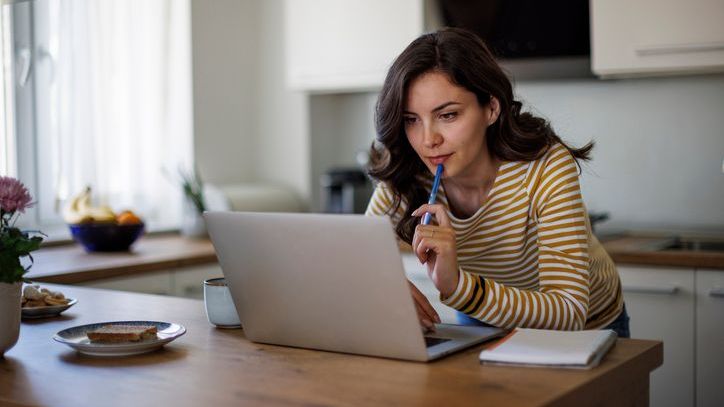 A woman does some research on a company's fundamentals from her kitchen.