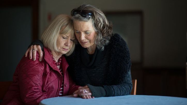A woman consoles her sister following the death her husband.