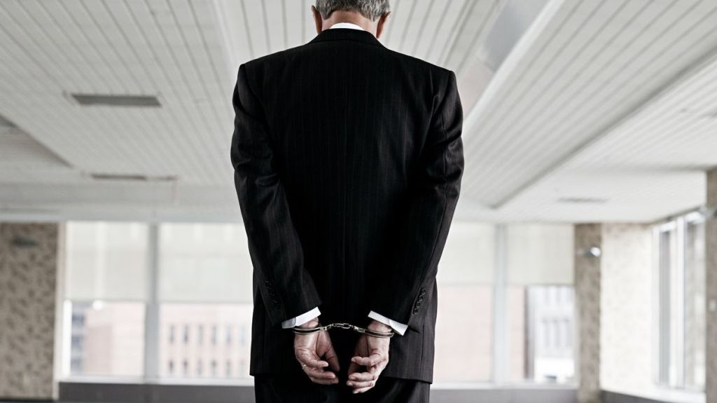 A financial advisor in handcuffs after being arrested on charges of fraud.