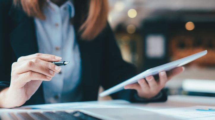 A wealth management advisor reviews a client's investment portfolio on her tablet.