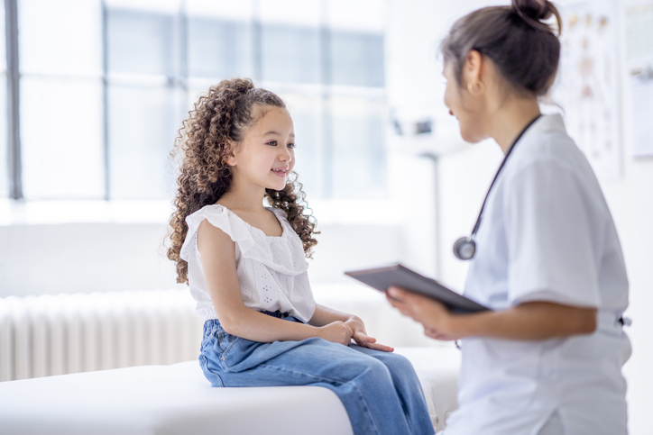 A young girl speaking with a doctor during a visit.