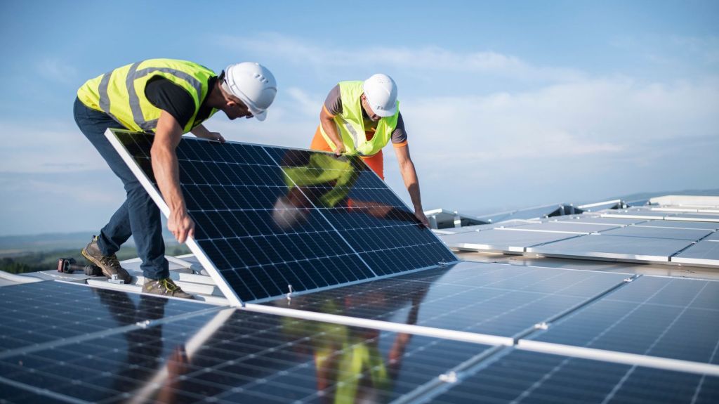 Workers install a solar panel on the roof of a building funded with green bonds.