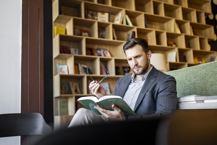 An investor reads a book for building wealth.