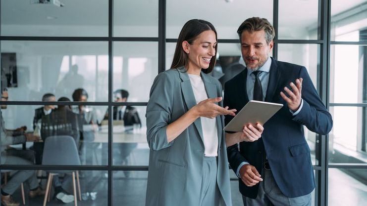 A pair of financial advisors review their firm's marketing proposal before going into a meeting.