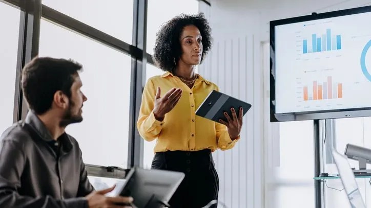 The financial manager of a company holds a tablet during a presentation to executive officers.