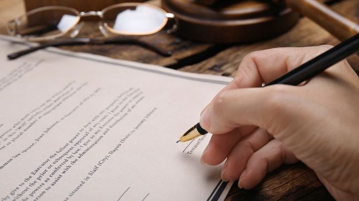 A woman signs her last will and testament, which will be validated in probate when she dies.