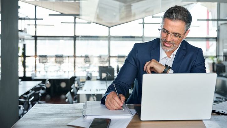 A finance professional who's in the process of starting a private equity fund takes notes during a Zoom call on his laptop.