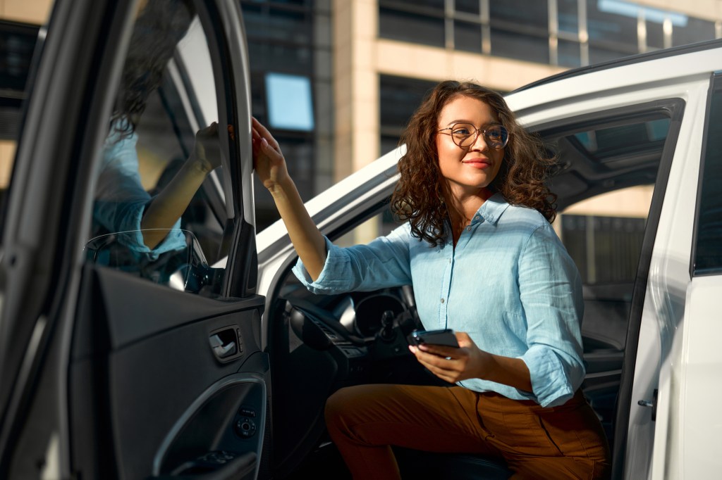 A woman inspecting a car before selling it.