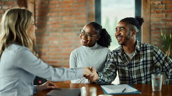 A couple shakes hands with a financial advisor after their initial consultation with her.