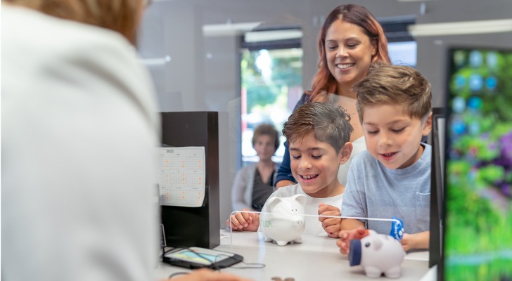 A mother with her children at a bank, making a deposit into their savings accounts.