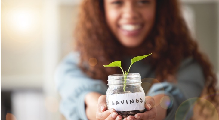 A woman holds a jar of coins.