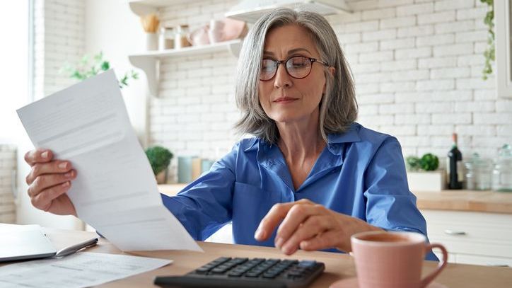 A woman looks over her monthly bills while budgeting her expenses.