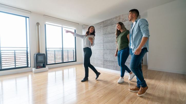 A property manager shows a pair of prospective clients an apartment unit owned by a real estate investor.
