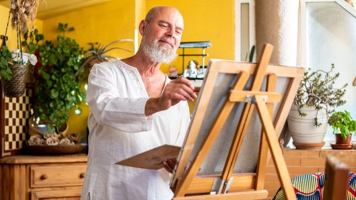 An artist works on a painting in his home studio.