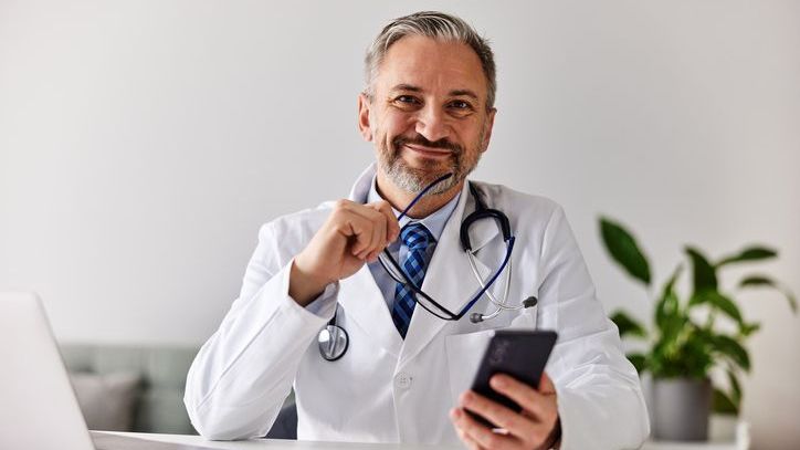 A doctor reviews his finances on his phone while considering his estate plan.