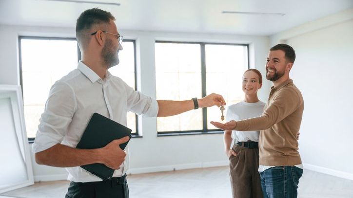 A tenant services worker hands the couple the keys to an apartment.