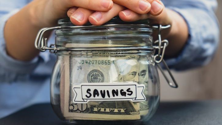 A man closes the lid on a savings jar that he occasionally puts spare cash in.